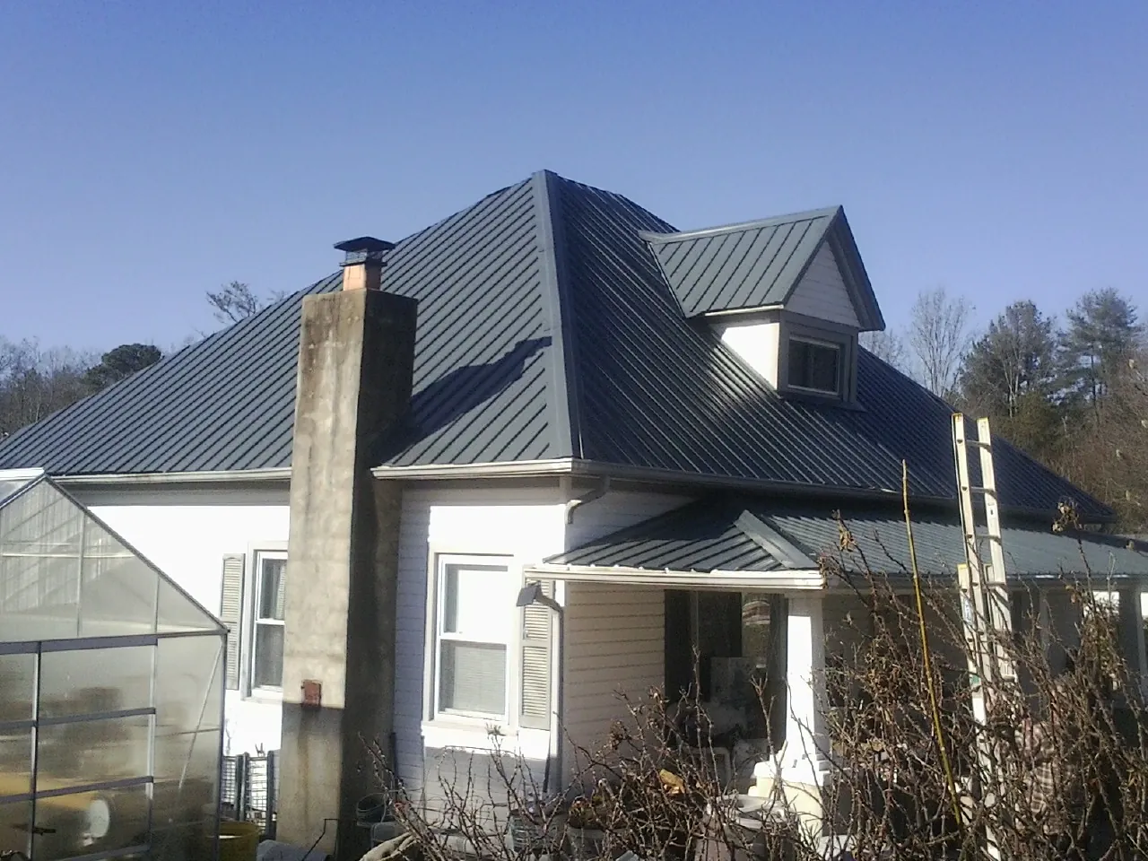 Dark blue standing seam metal roof on a white farmhouse with dormer — Slate & Tile Roof Repair by Roofing Brothers in Mahopac Falls