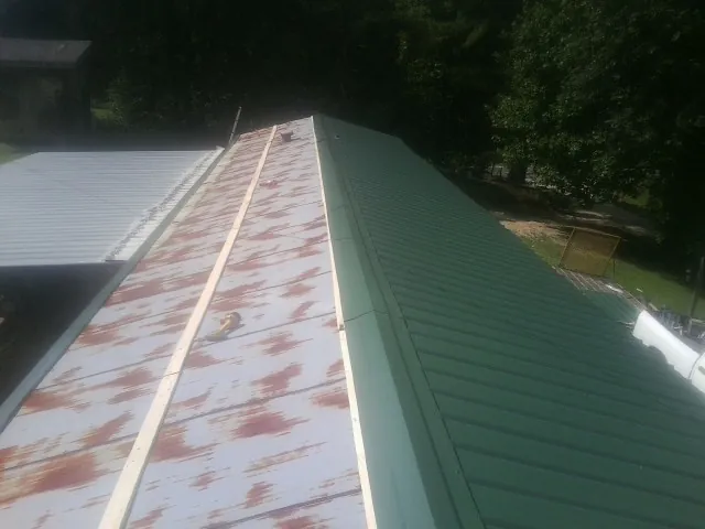 Old rusted panels beside newly installed green metal roofing — Wind Damage Roof Repair by Roofing Brothers in Mahopac Falls