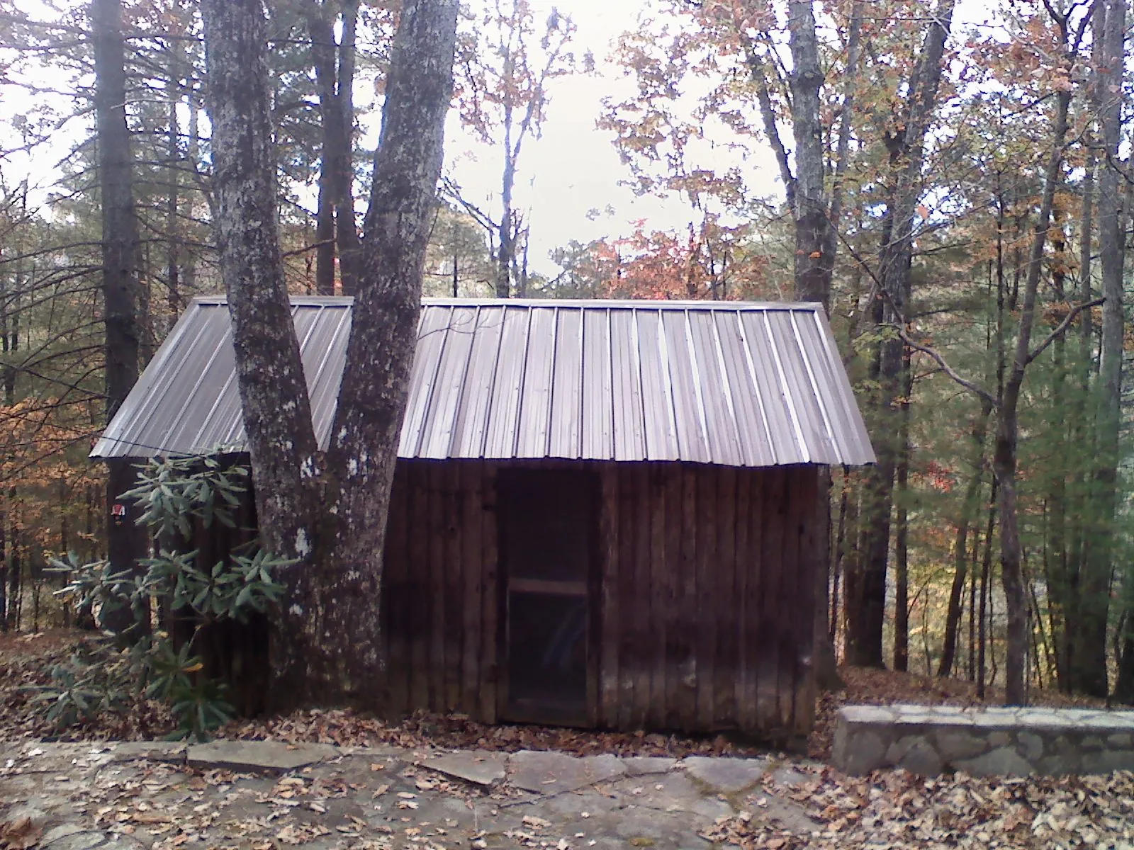 New metal gable roof on a small log shed among the trees in Mahopac Falls