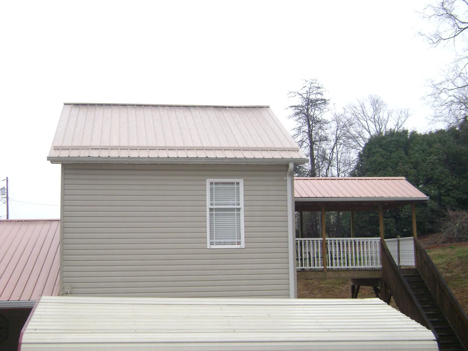 Tan metal roofs on a two story addition and attached porch, from a Roof Replacement job in Mahopac Falls