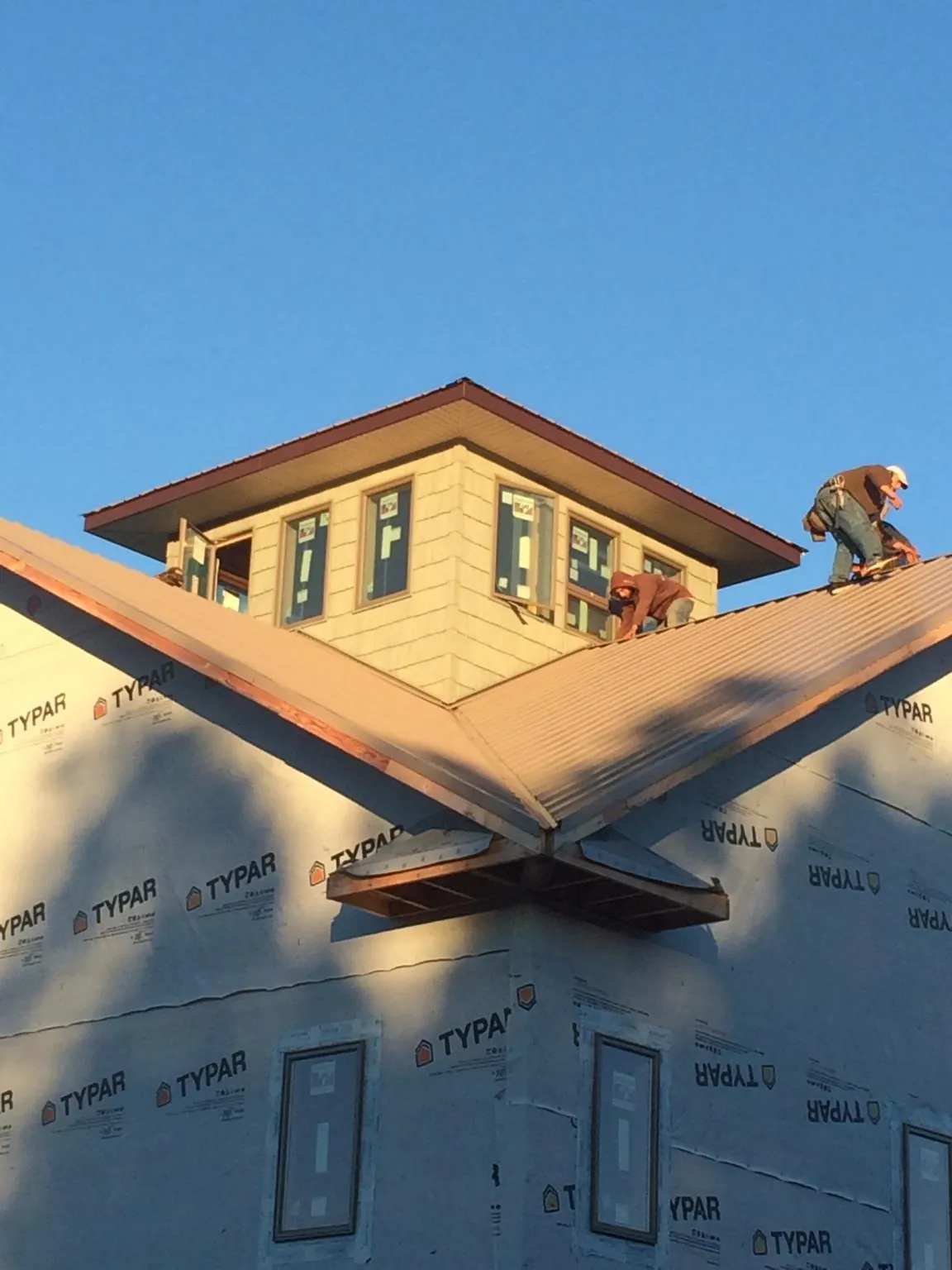 Roofers working around a rooftop cupola on a new metal roof at sunset — Roof Waterproofing in Mahopac Falls by Roofing Brothers